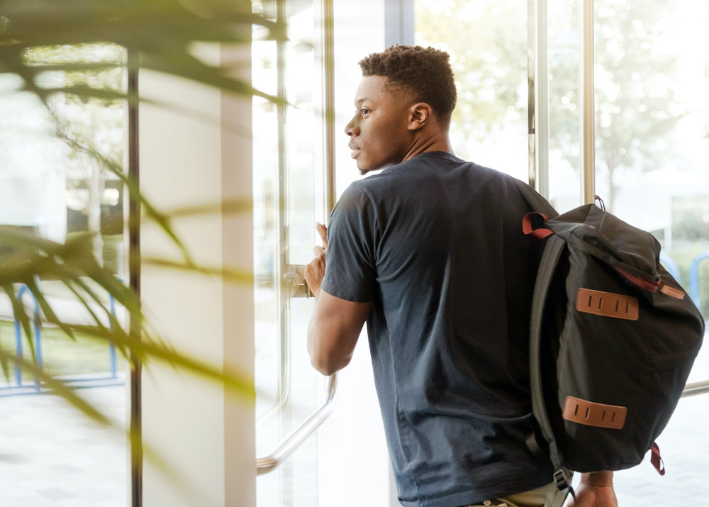 black man with backpack walking out glass doors, online adult ADHD testing, OAT