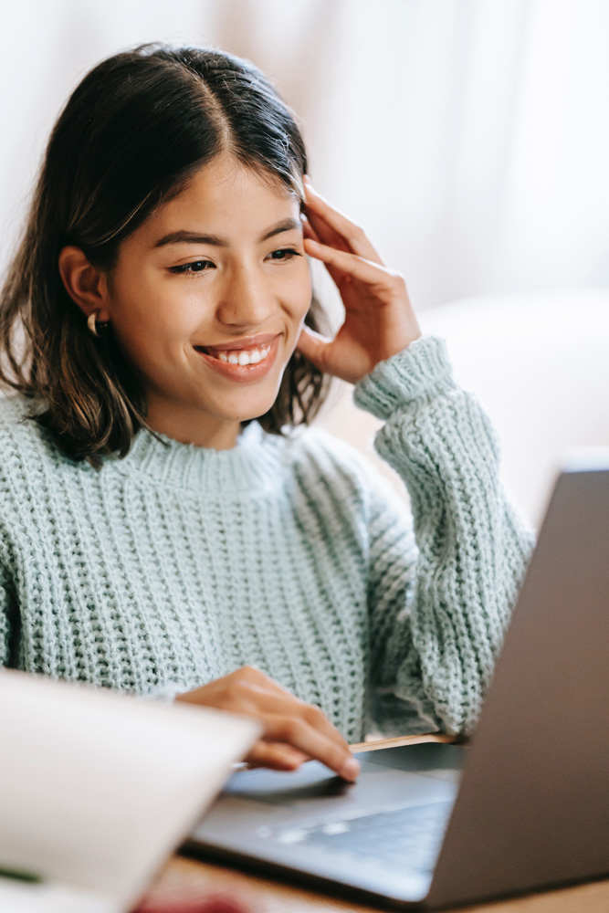 indian woman at computer smiling, online adult testing, ADHD, ASD, OAT