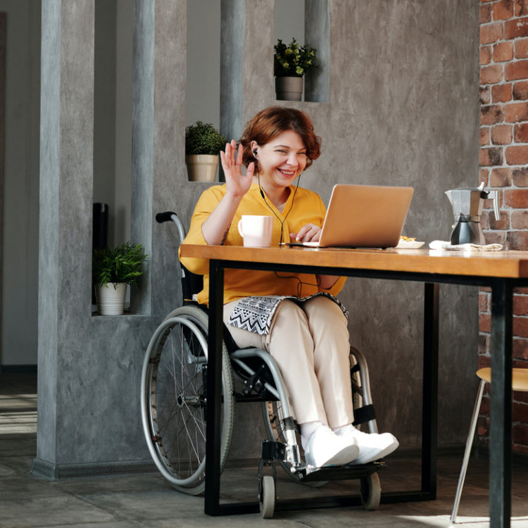 woman in wheelchair smiling and waving at laptop, online psychological assessment, OAT